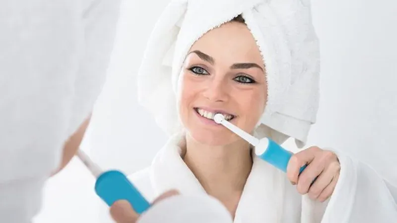 Ultraschallzahnbürste und frau mit weißen zähnen